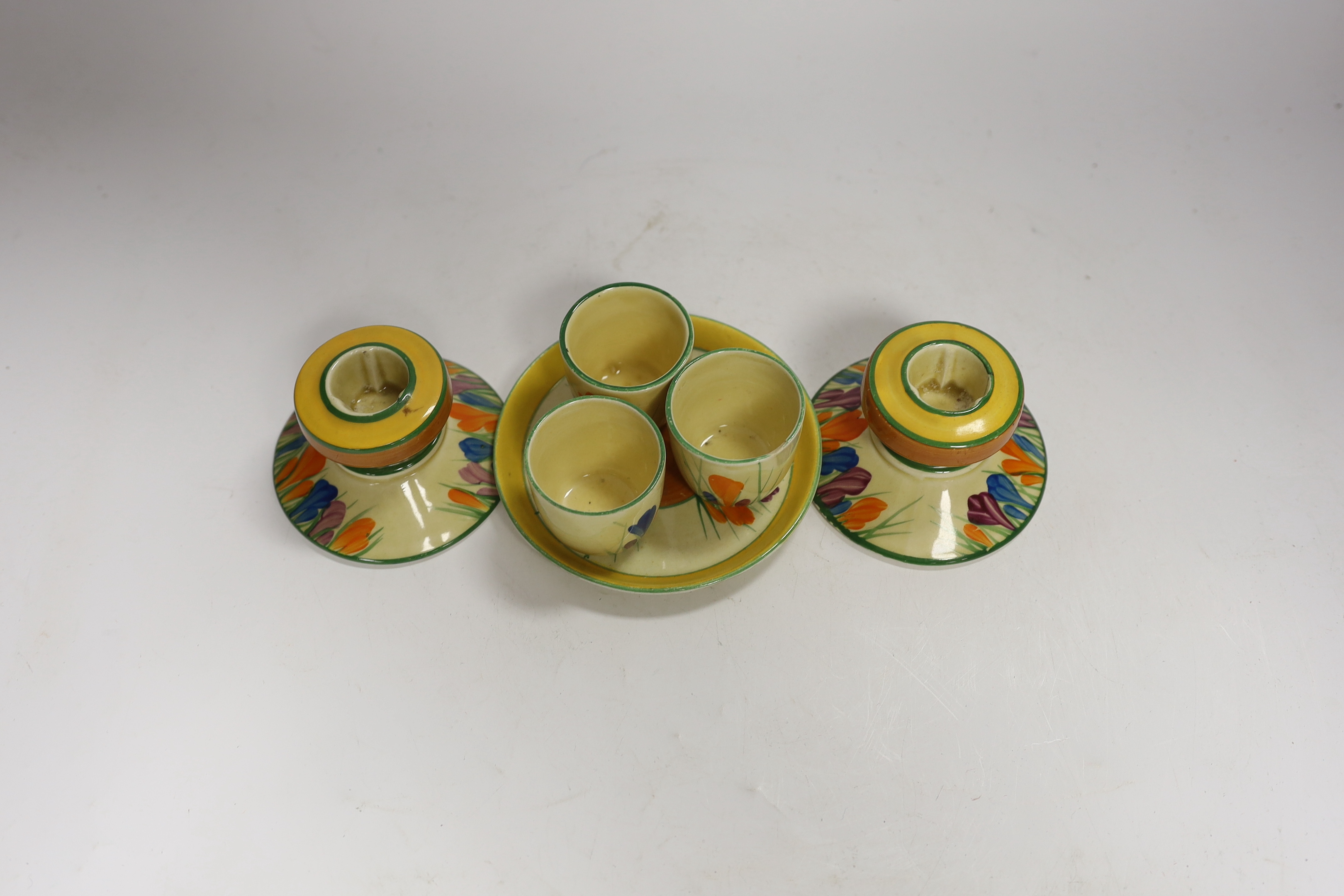 Clarice Cliff Crocus pattern items; a pair of candlesticks, 5cm high and three egg cups with stand